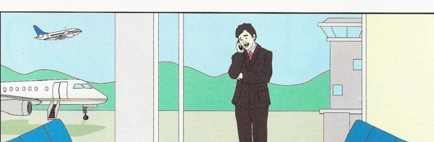 A man in a dark suit talking on the phone at an airport, with a plane outside the window and a small suitcase beside him
